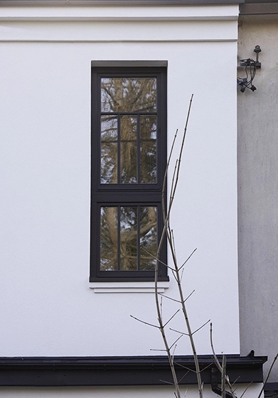 Zbliżenie na nowoczesne okno ze szprosami w projekcie przebudowy domu.